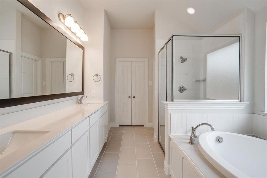 Bathroom featuring vanity, tile patterned flooring, and shower with separate bathtub