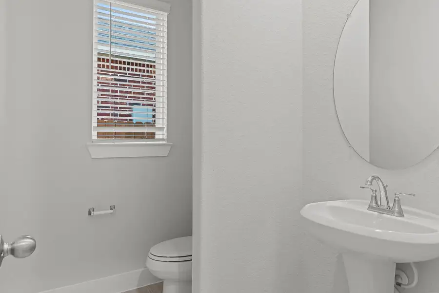 The convenient half bath on the main floor is perfect for guests! This beautifully finished space features a sleek pedestal sink, contemporary lighting, and soft natural tones that complement the home’s bright and airy feel.