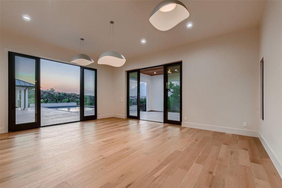 This spacious area features light wood flooring and offers extensive views through large glass doors