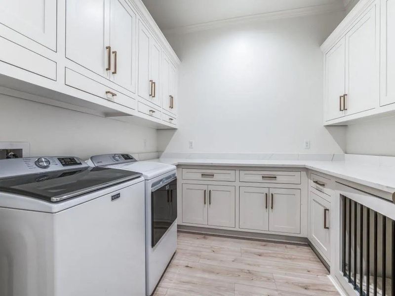 Laundry room featuring light wood finished floors, independent washer and dryer, cabinet space, crown molding, and wine cooler