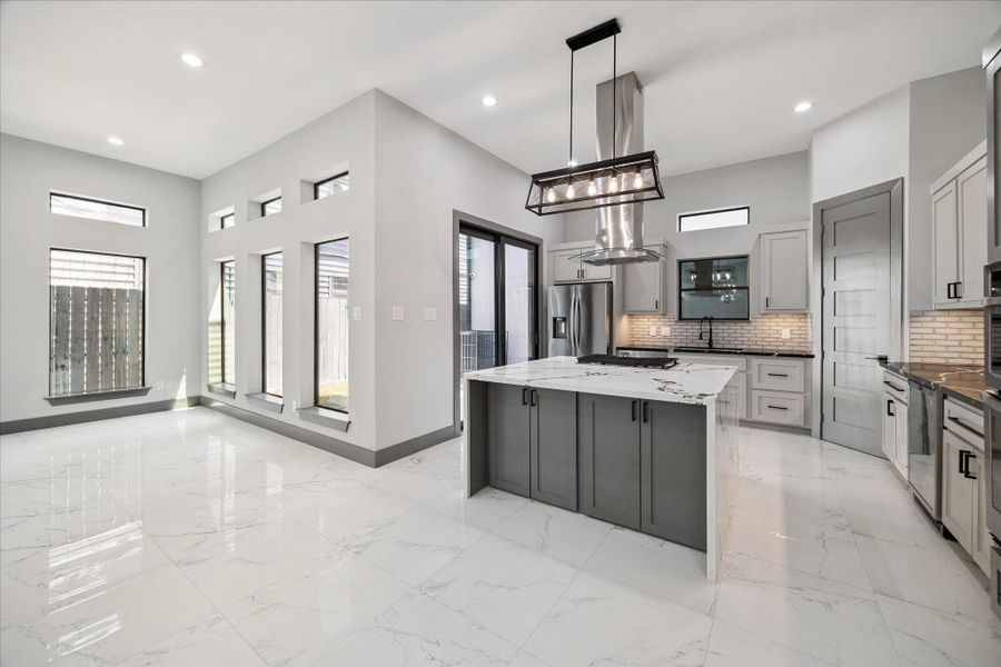 Bright and open, the layout flows effortlessly from kitchen to living area, with walls of windows, a spacious island for gathering, and flexible space for both dining and entertaining. Contemporary finishes and thoughtful details ensure cohesion and style.