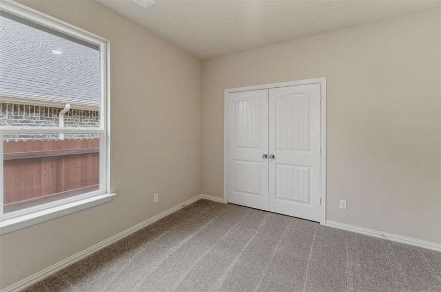 Light-filled interior space featuring neutral wall paint, white trim, and gray patterned carpeting