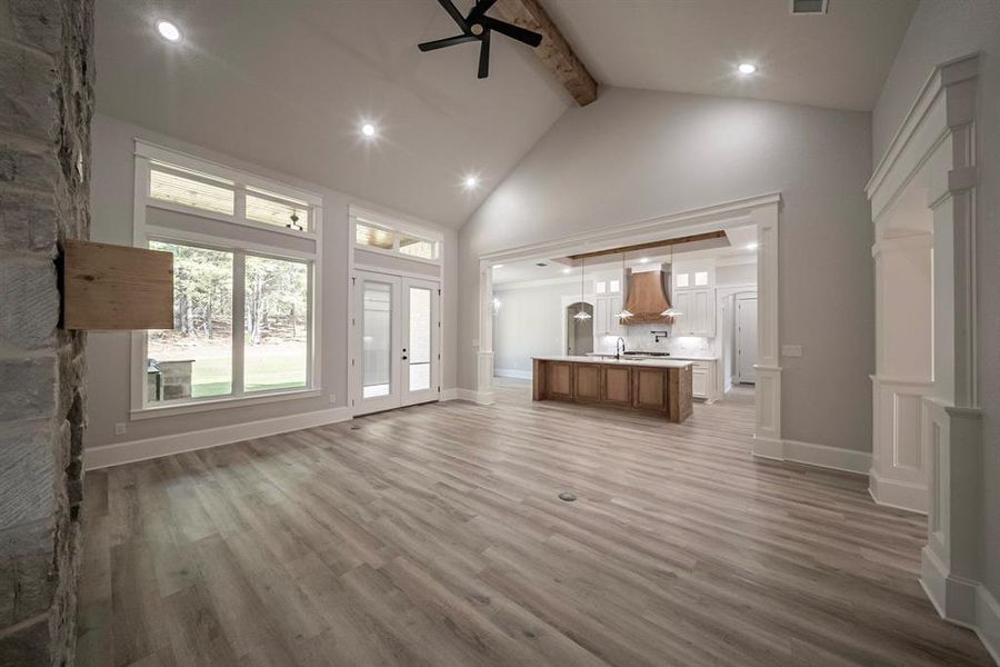 Unfurnished living room featuring beam ceiling, light wood finished floors, a ceiling fan, recessed lighting, and high vaulted ceiling Unfurnished living room featuring beam ceiling, light wood finished floors, a ceiling fan, recessed lighting, and high vaulted ceiling