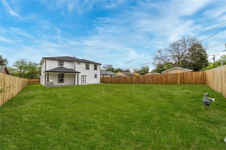 Rear view of house with a fenced backyard and a patio area