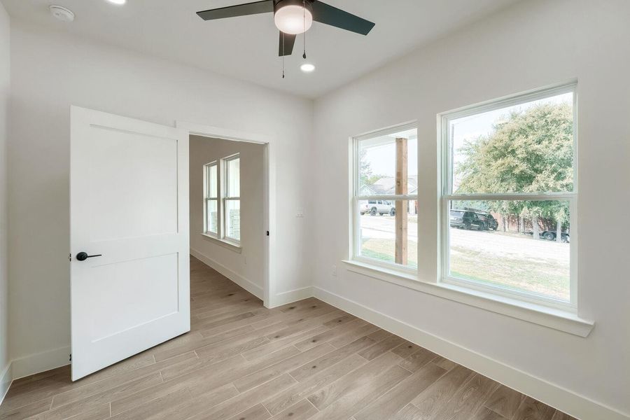 Bright interior space features light wood-look tile flooring and multiple windows framing neighborhood views.