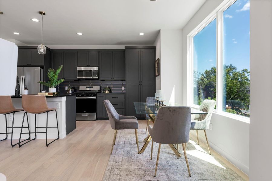 Kitchen featuring a breakfast bar area, backsplash, appliances with stainless steel finishes, decorative light fixtures, and recessed lighting