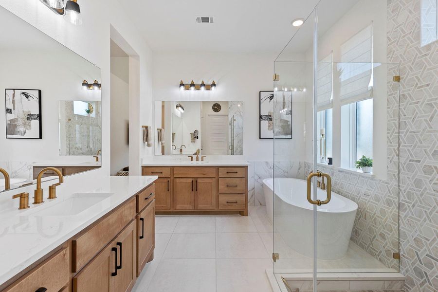 Luxurious primary bathroom featuring dual vanities, a soaking tub, and a frameless glass shower with designer tile accents.