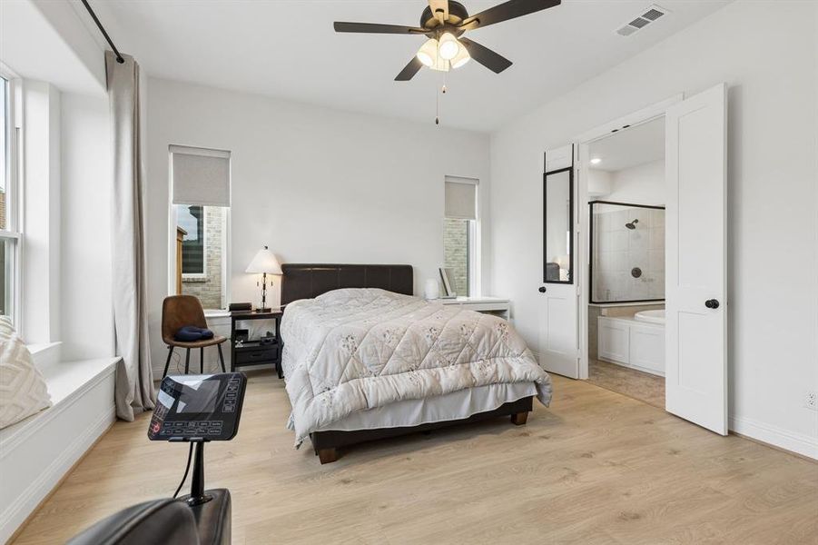 Bedroom with light wood-finish flooring, vaulted ceiling, and ceiling fan