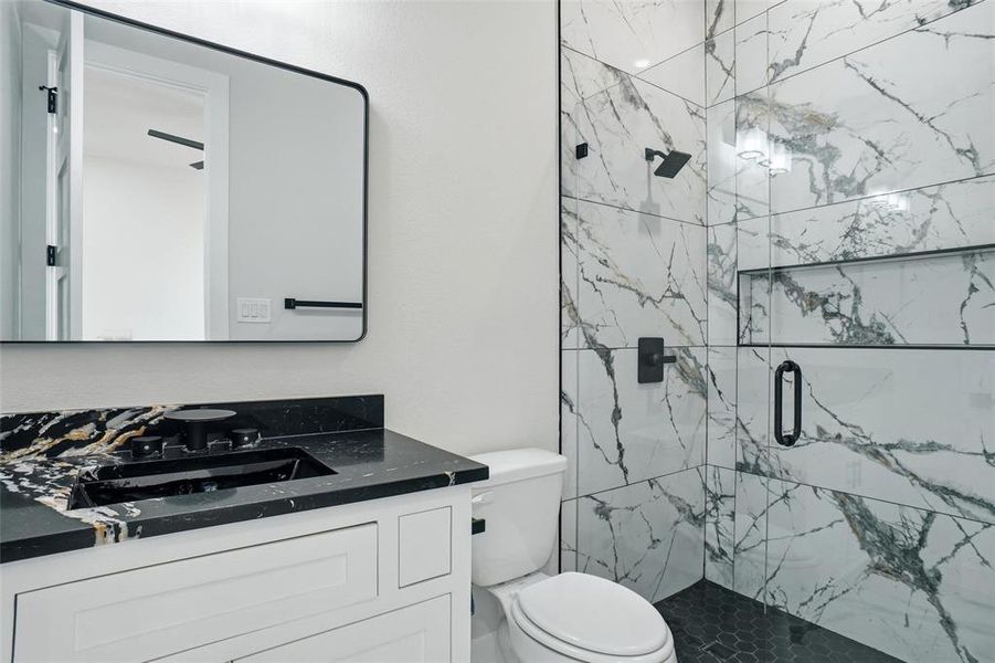 Private ensuite bathroom featuring a walk-in glass shower with designer tile and modern finishes.
