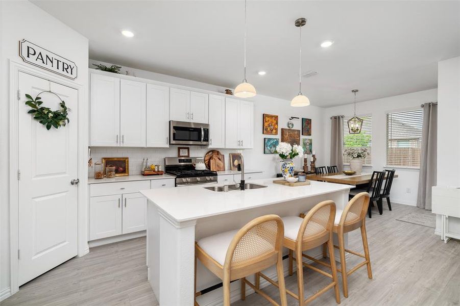 The open-concept kitchen features white cabinetry, stainless steel appliances, and a central island with counter seating