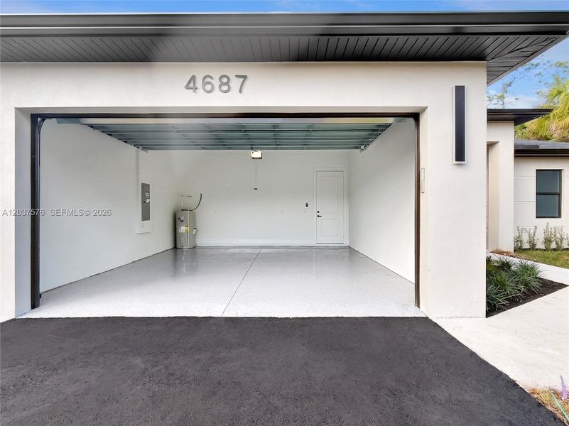 Spacious garage featuring a finished floor coating, recessed lighting, a built-in water heater, and direct access to interior spaces
