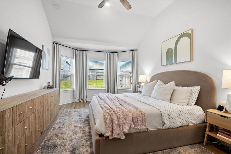 Relax and unwind in the spacious primary suite, featuring a vaulted ceiling and beautiful bay windows that fill the room with natural light and create a bright, peaceful retreat.