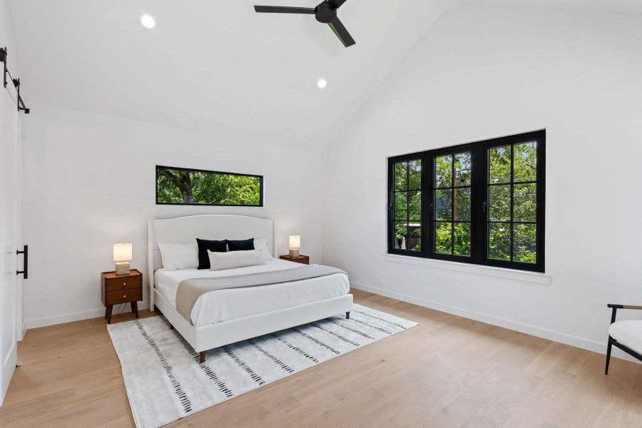 Natural light streams into this primary bedroom, featuring a vaulted ceiling and ample hardwood flooring. Natural light streams into this primary bedroom, featuring a vaulted ceiling and ample hardwood flooring.