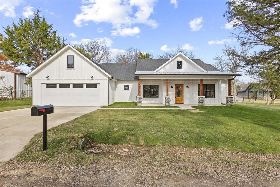 Modern farmhouse style home with board and batten siding, concrete driveway, covered porch, a front yard, and roof with shingles