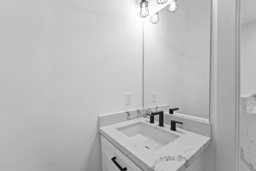 The half bath on the main level is an elevated design, quartz finishes, and black matte fixtures for a clean, modern feel. The half bath on the main level is an elevated design, quartz finishes, and black matte fixtures for a clean, modern feel.