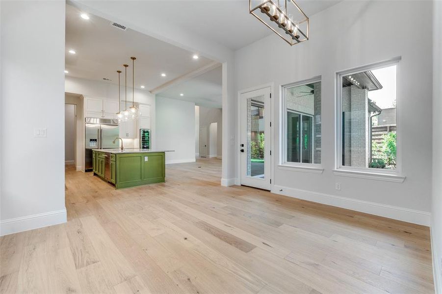 Kitchen featuring green cabinets, a center island with sink, light wood finished floors, white cabinetry, and recessed lighting Kitchen featuring green cabinets, a center island with sink, light wood finished floors, white cabinetry, and recessed lighting