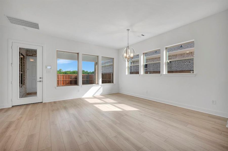 Unfurnished room featuring a chandelier and light wood finished floors Unfurnished room featuring a chandelier and light wood finished floors