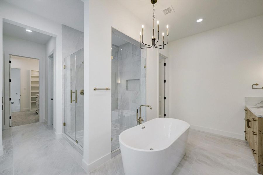 Primary Bath – Features a luxurious freestanding soaking tub and an oversized walk-in shower with frameless glass door.