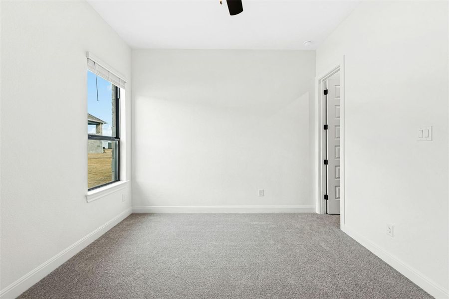 Carpeted empty room featuring a ceiling fan and baseboards