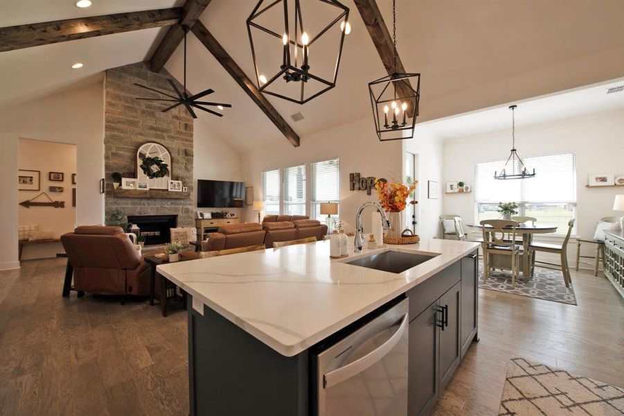 Kitchen featuring hanging light fixtures, high vaulted ceiling, beam ceiling, stainless steel dishwasher, and a fireplace