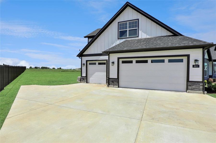View of front of property with board and batten siding, stone siding, driveway, a shingled roof, and an attached garage View of front of property with board and batten siding, stone siding, driveway, a shingled roof, and an attached garage