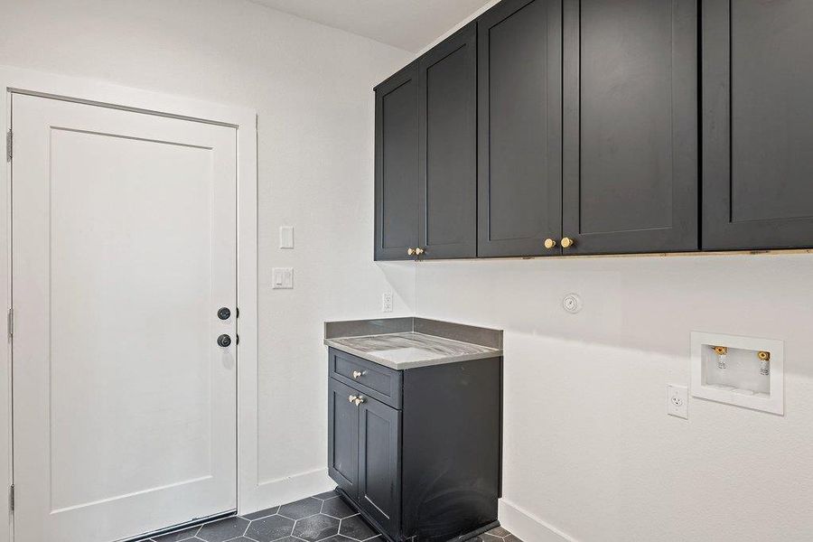 Washroom featuring hookup for a washing machine, dark tile patterned floors, and cabinet space