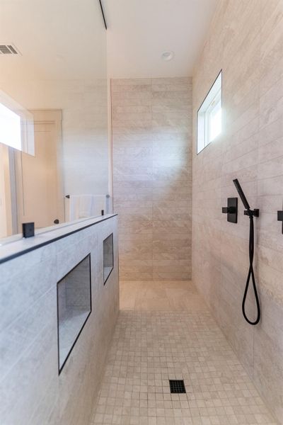 Bathroom featuring tiled shower and tile walls Bathroom featuring tiled shower and tile walls