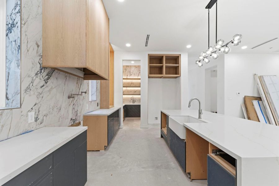 This chef's kitchen is thoughtfully designed and will house a free-standing Thermador range. Enhancing the aesthetics of the kitchen is a porcelain accent wall, waterfall quartz countertops, and a farmhouse sink. This chef's kitchen is thoughtfully designed and will house a free-standing Thermador range. Enhancing the aesthetics of the kitchen is a porcelain accent wall, waterfall quartz countertops, and a farmhouse sink.