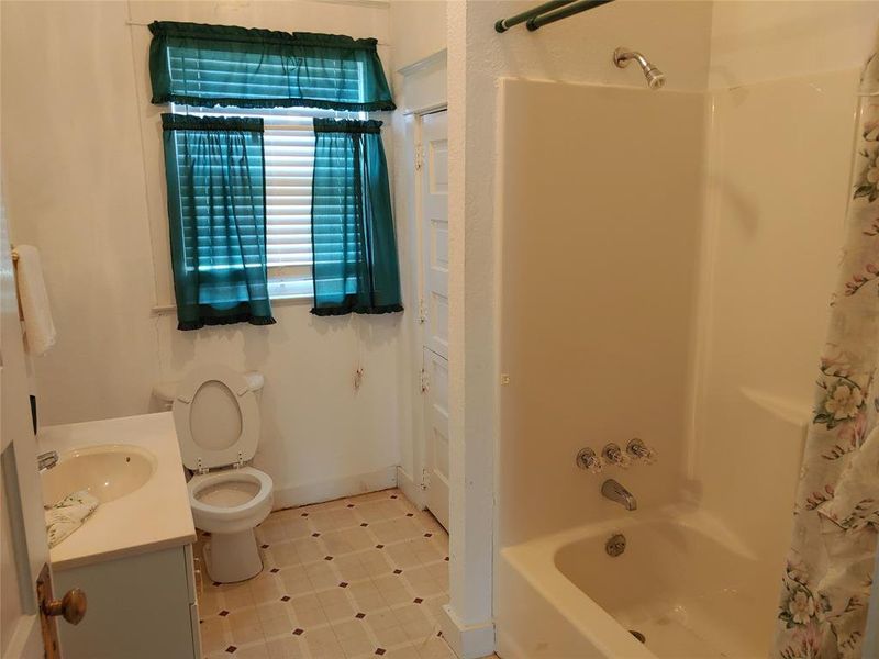 Upstairs guest bathroom featuring a white vanity with integrated sink, toilet, and a combined tub/shower unit Upstairs guest bathroom featuring a white vanity with integrated sink, toilet, and a combined tub/shower unit