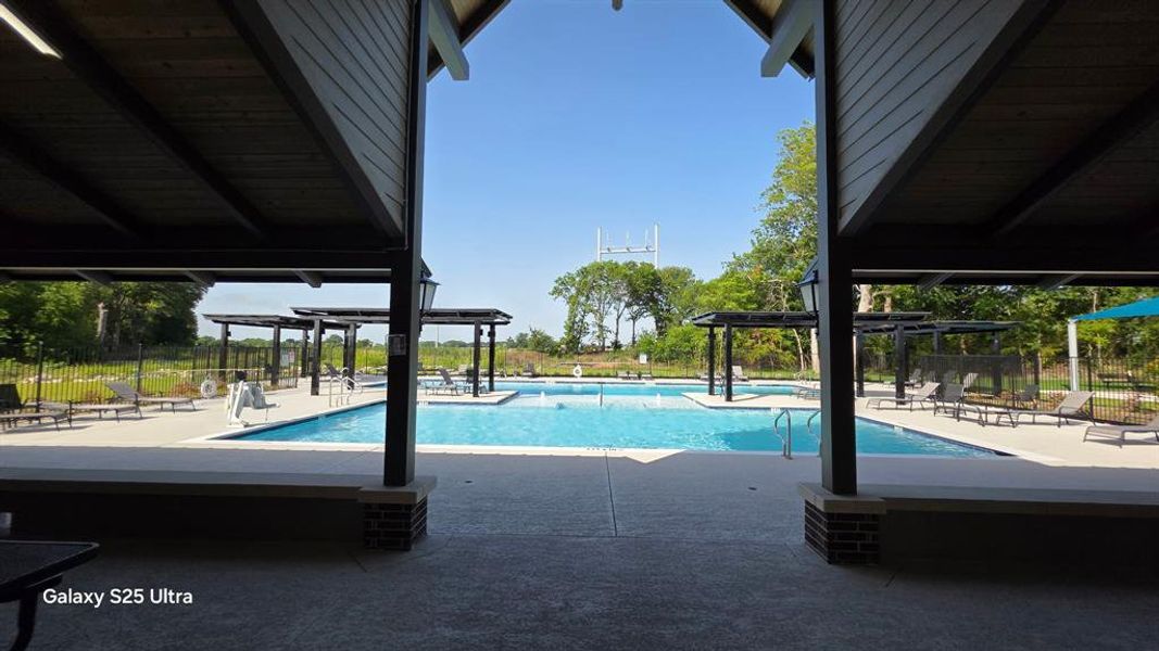 Community swimming pool with an expansive concrete deck, multiple lounge areas, decorative pergolas, and integrated water features Community swimming pool with an expansive concrete deck, multiple lounge areas, decorative pergolas, and integrated water features