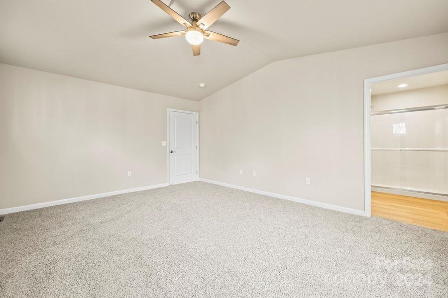 Vaulted ceiling with ceiling fan in the primary bedroom