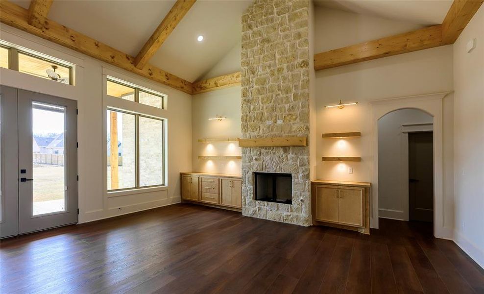 Unfurnished living room with a fireplace, dark wood-style floors, french doors, vaulted ceiling, and arched walkways Unfurnished living room with a fireplace, dark wood-style floors, french doors, vaulted ceiling, and arched walkways