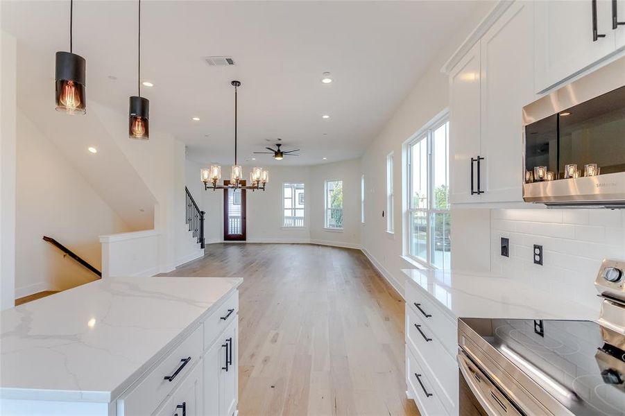 Kitchen with pendant lighting, ceiling fan, white cabinetry, and stainless steel appliances