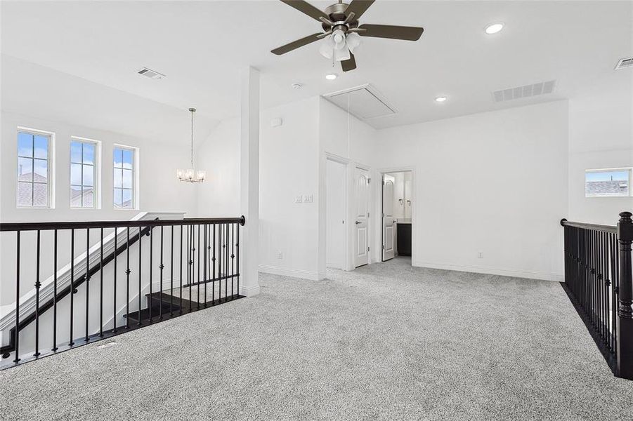 Carpeted spare room with ceiling fan with notable chandelier