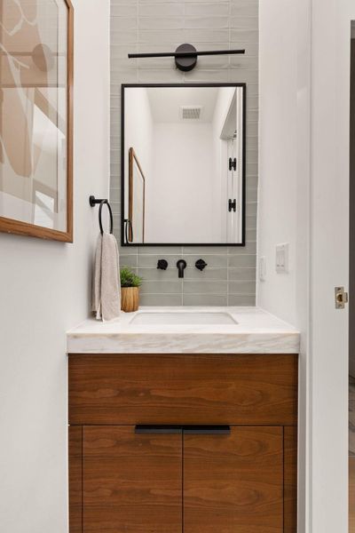 A refined bathroom vanity featuring rich wood cabinetry, a sleek white sink, and contemporary fixtures.