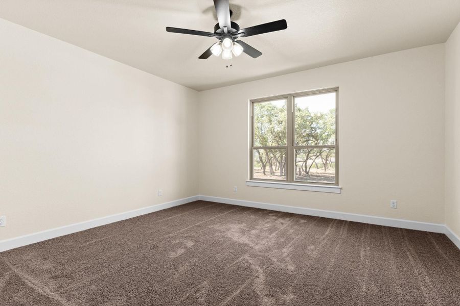 Empty room featuring dark colored carpet and ceiling fan Empty room featuring dark colored carpet and ceiling fan