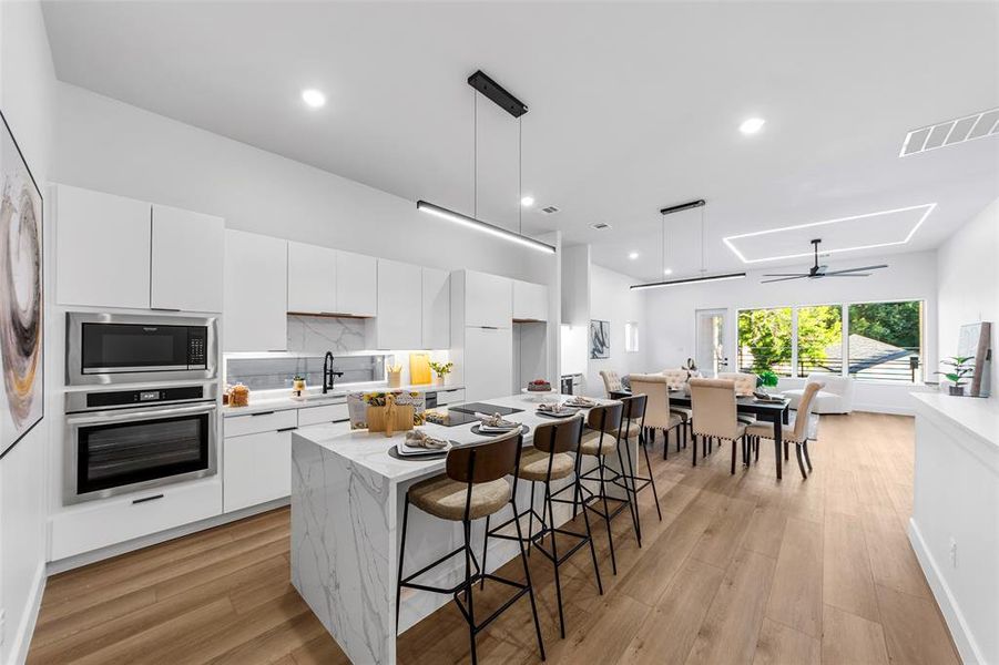 Kitchen with white cabinetry, a kitchen island, decorative light fixtures, modern cabinets, and decorative backsplash Kitchen with white cabinetry, a kitchen island, decorative light fixtures, modern cabinets, and decorative backsplash