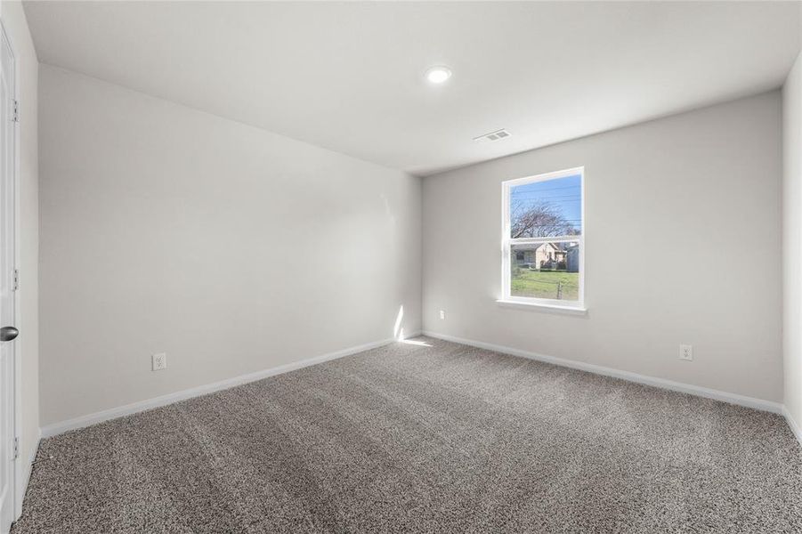 Carpeted empty room featuring visible vents and baseboards