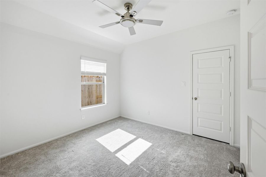 Bright and airy bedroom, soft carpet, a modern ceiling fan, and ample natural light from a large window.
