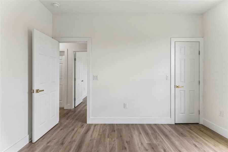 Natural wood flooring complements clean white walls, creating an inviting, versatile living space.