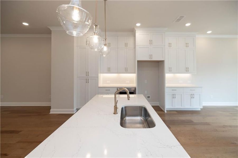 Kitchen with white cabinetry, sink, decorative light fixtures, and light stone countertops