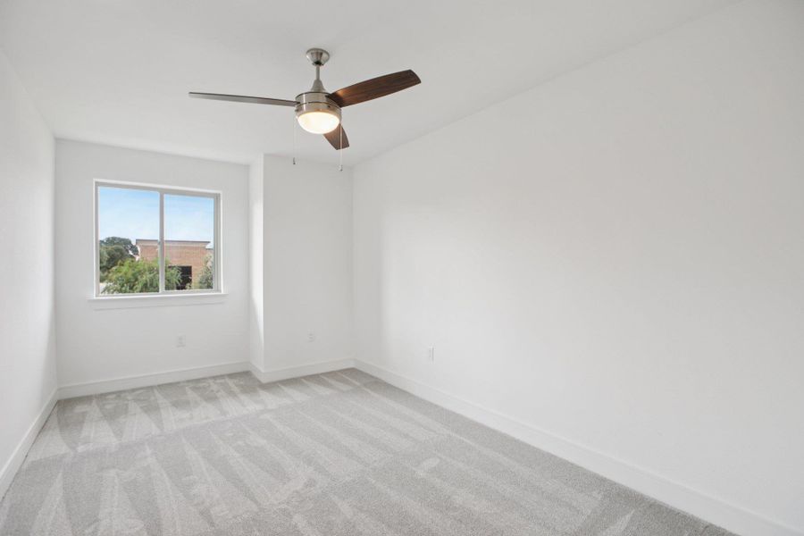 Unfurnished room featuring light carpet and a ceiling fan