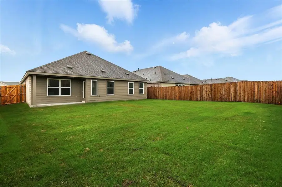 Back of house with a fenced backyard and a shingled roof