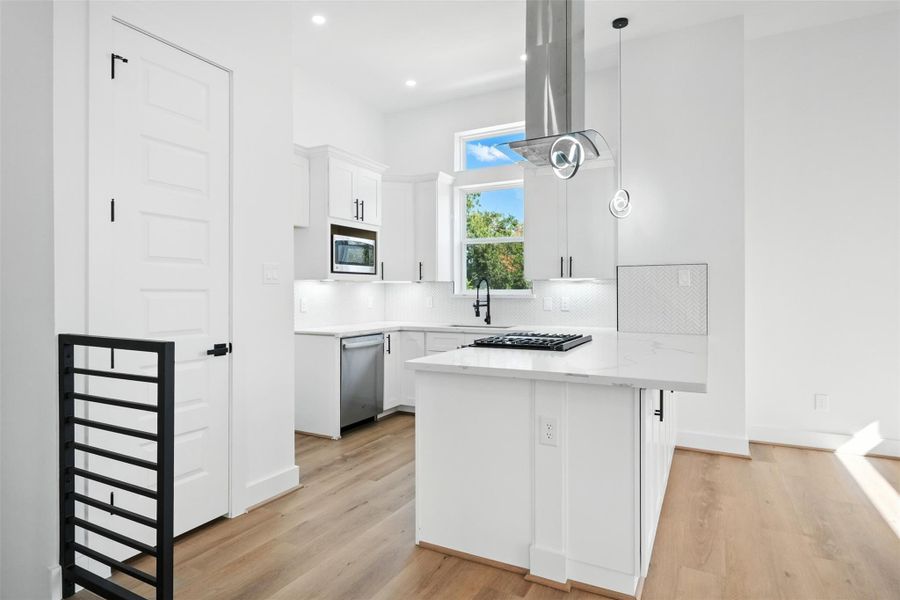 Open-concept kitchen with clean, contemporary finishes, featuring Quartz countertops, custom soft-close cabinetry, and a sleek herringbone tile backsplash. Equipped with a gas cooktop, stainless steel appliances, designer lighting, and abundant natural light. Open-concept kitchen with clean, contemporary finishes, featuring Quartz countertops, custom soft-close cabinetry, and a sleek herringbone tile backsplash. Equipped with a gas cooktop, stainless steel appliances, designer lighting, and abundant natural light.