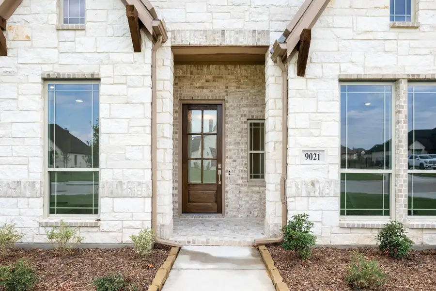 Front entry of stone home with wood door, arched alcove, and house number 9021 Front entry of stone home with wood door, arched alcove, and house number 9021