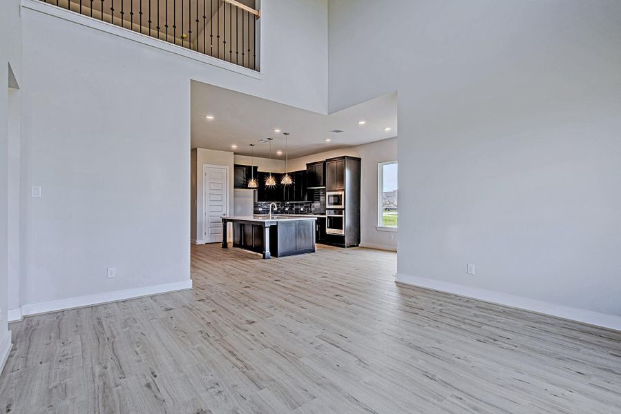 Spacious living area seamlessly connects to the kitchen and dining spaces, accented by volume ceilings and a sleek iron railing on the second-floor landing. Spacious living area seamlessly connects to the kitchen and dining spaces, accented by volume ceilings and a sleek iron railing on the second-floor landing.
