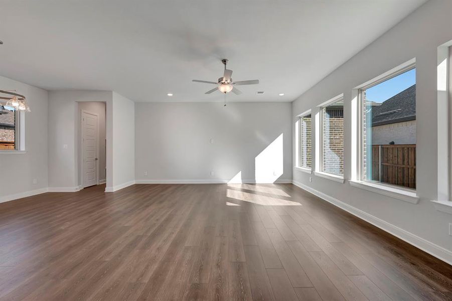 Unfurnished living room featuring dark wood-style floors, ceiling fan, and recessed lighting
