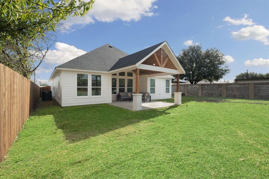 Rear view of property featuring a shingled roof, a fenced backyard, and a patio area Rear view of property featuring a shingled roof, a fenced backyard, and a patio area