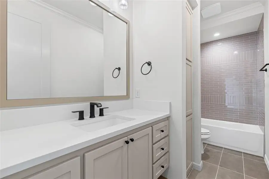Bathroom featuring vanity, shower / tub combination, light tile patterned flooring, crown molding, and recessed lighting