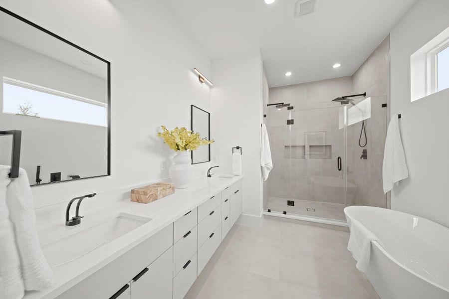 Beautifully appointed, the owner's private bath includes a floating vanity with white cabinetry supporting a Quartz countertop, dual undermount sinks, oversized black framed mirrors with lighting above and 12’ x 24” tile floors.